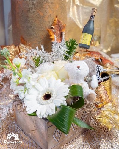 Composition florale du Nouvel An blanche et argentée avec gerbera, roses, décor doré et mini champagne